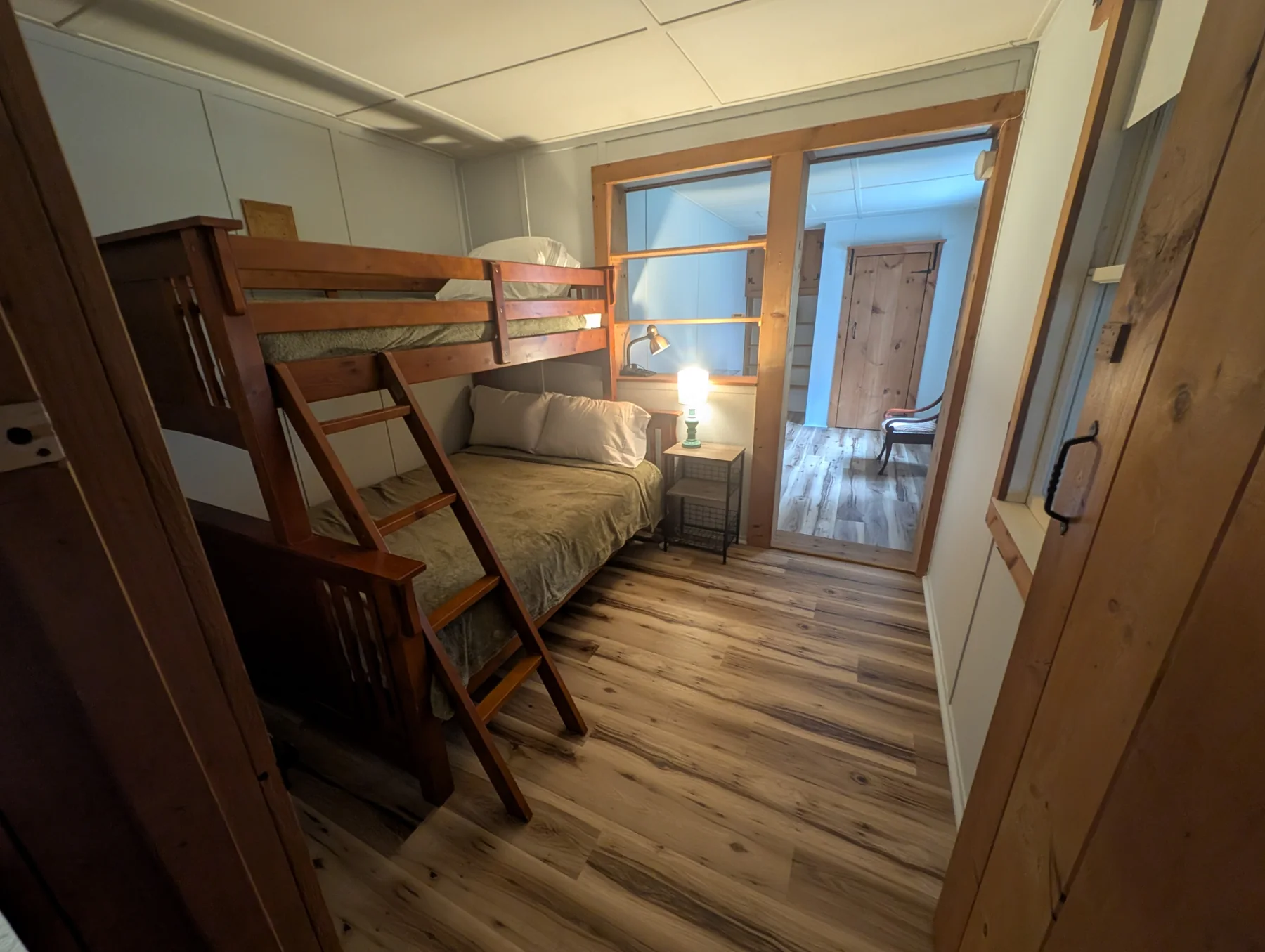 Bunk sleeping nook with ladder, upper bunk, lower bed, and reading lamp