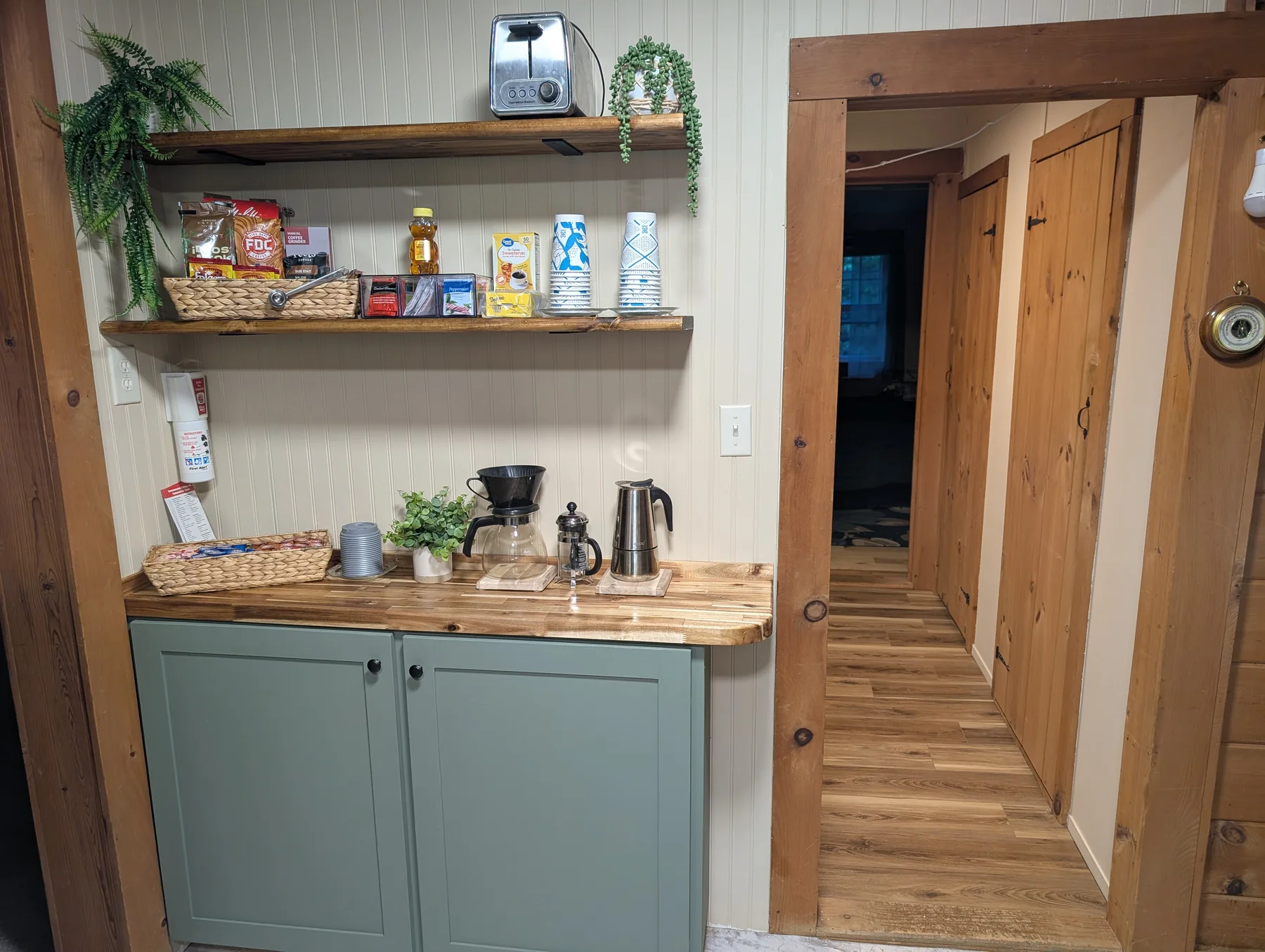 Coffee and tea station with pour-over setup, cups, pantry shelves, and green cabinetry