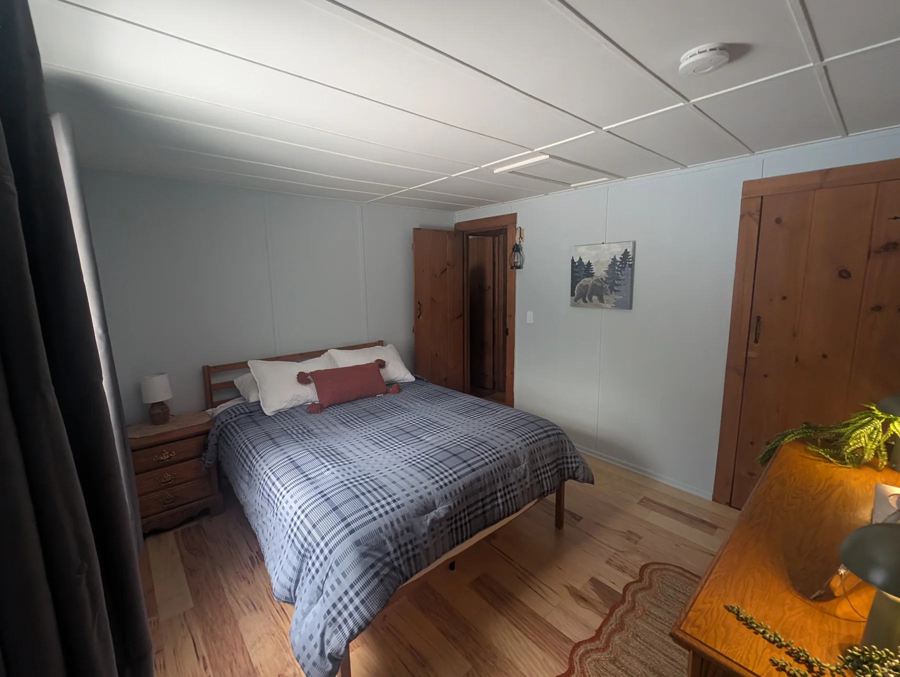 Guest bedroom with a large bed, bedside table, dresser, and wood trim
