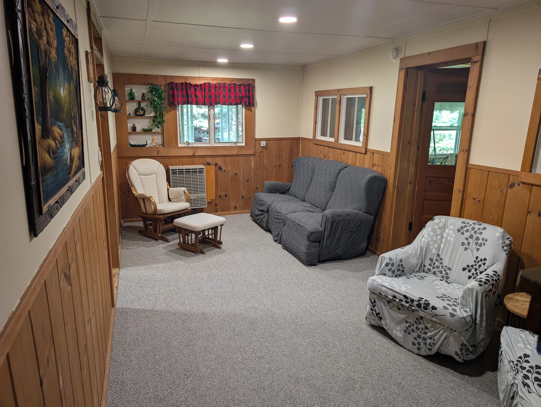 Lower lounge with sofa, reading chair, rocking chair, and wood-paneled walls